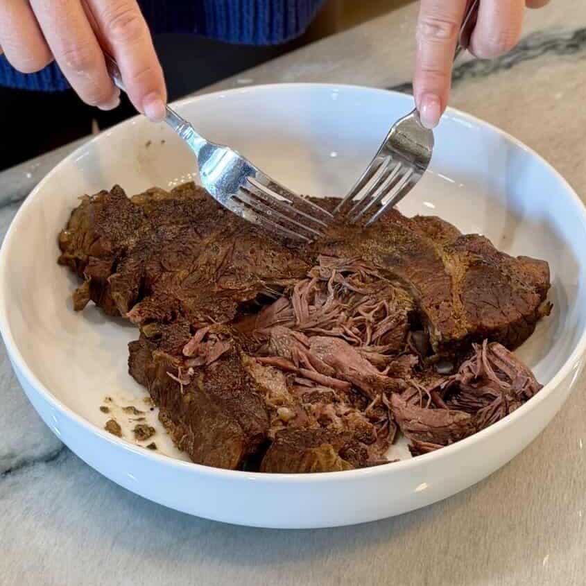 Shredding the beef in the bowl.